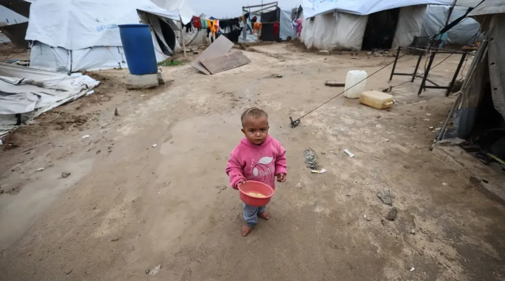Gazze Şeridi'nin merkezindeki el-Bureyc Mülteci Kampı’nda, yerinden edilmiş Filistinliler için kurulan geçici barınakların arasında duran bir çocuk (AFP)