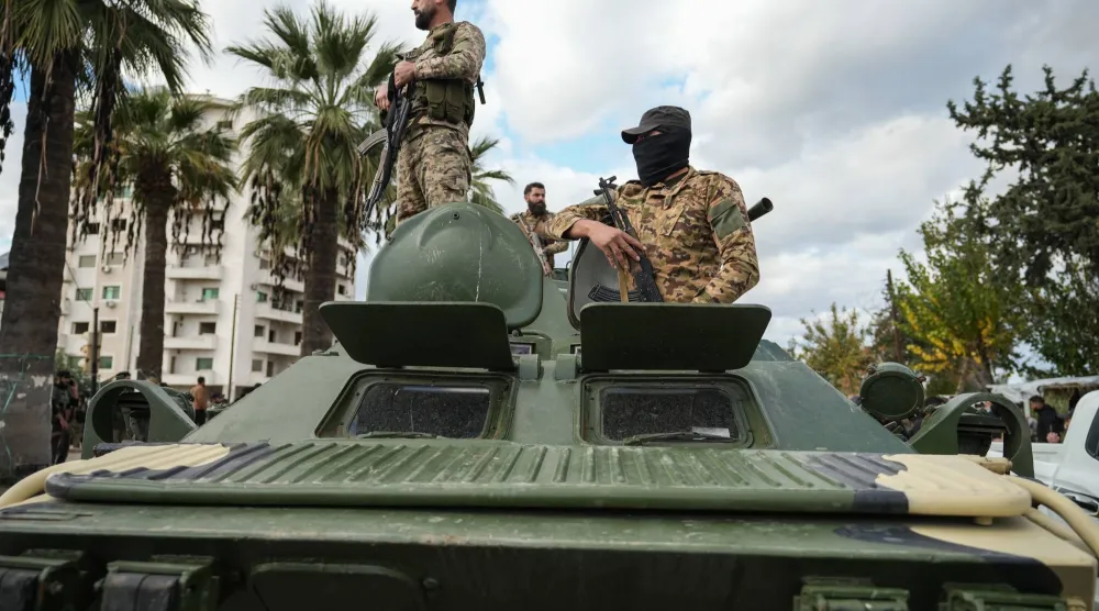 عناصر من القوات السورية يقفون فوق مركبة عسكرية عقب اندلاع اشتباكات في مدينة اللاذقية (إ.ب.أ)