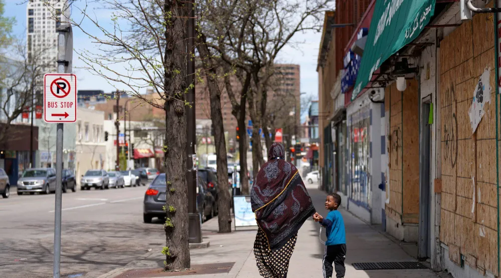  سيدة وطفلها في أحد الأحياء التي تقطنها الجالية الصومالية في مينيابوليس مايو 2022 (أ.ب)