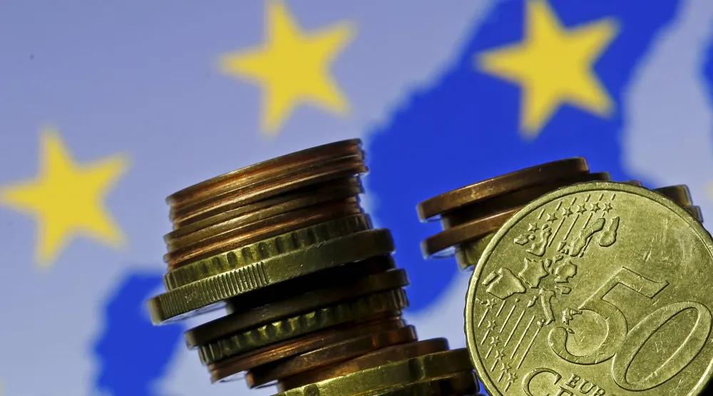 تُظهر هذه الصورة التوضيحية عملات اليورو أمام علم وخريطة الاتحاد الأوروبي (رويترز)