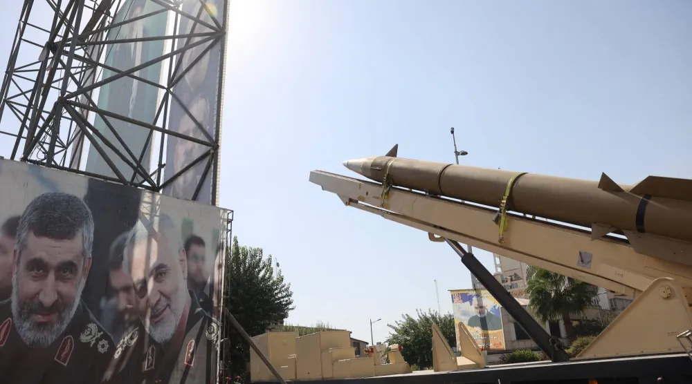 صاروخ باليستي إيراني يُعرض في شارع وسط طهران بجوار لافتة تحمل صورة المسؤول السابق للعمليات الخارجية في «الحرس الثوري» قاسم سليماني ومسؤول البرنامج الصاروخي أمير علي حاجي زادة الذي قُتل بضربة إسرائيلية في يونيو الماضي (رويترز)