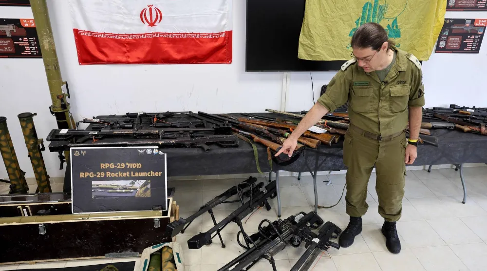 ضابط إسرائيلي يستعرض خلال جولة إعلامية وسائل قتالية ضبطها الجيش في غزة ولبنان وسوريا (أ.ف.ب)