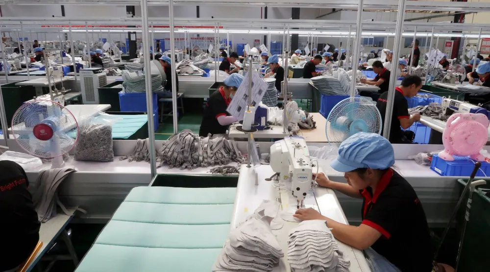 عمال في مصنع لملابس وألعاب الأطفال في مدينة جيوجيانغ وسط الصين (رويترز)