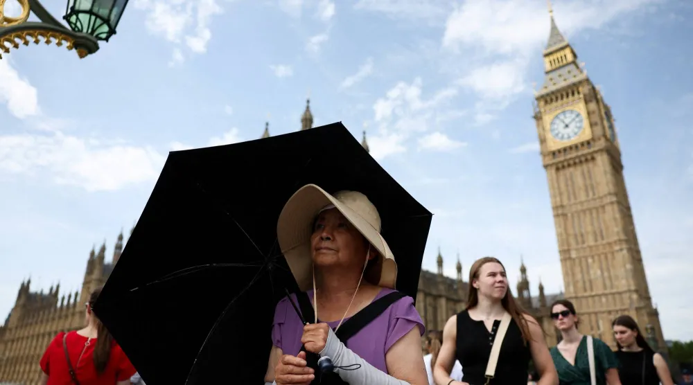 FILE PHOTO: A woman shields herself from sun with an umbrella at Westminster Bridge in London, Britain, June 21, 2025. REUTERS/Isabel Infantes/File Photo
