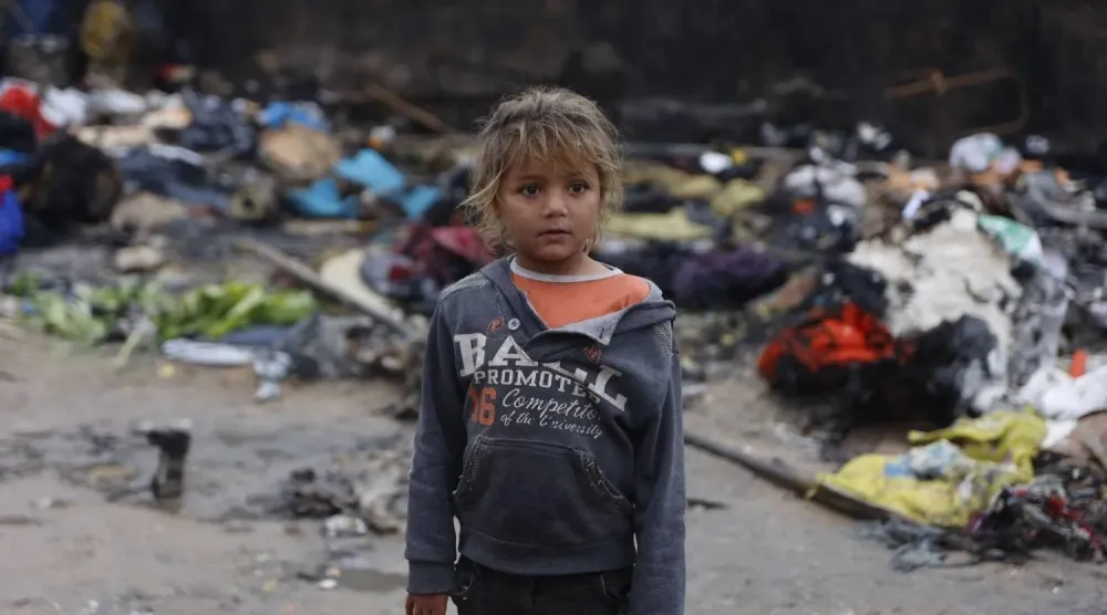 A young girl stands in front of tents that burned after candles were lit for lighting at a displacement camp in Gaza City on Friday (AFP)