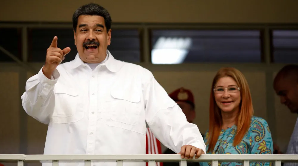 الرئيس الفنزويلي نيكولاس مادورو يتحدث إلى وسائل الإعلام بجانب زوجته سيليا فلوريس بعد مشاركته في تدريب على التصويت عام 2018 (رويترز)