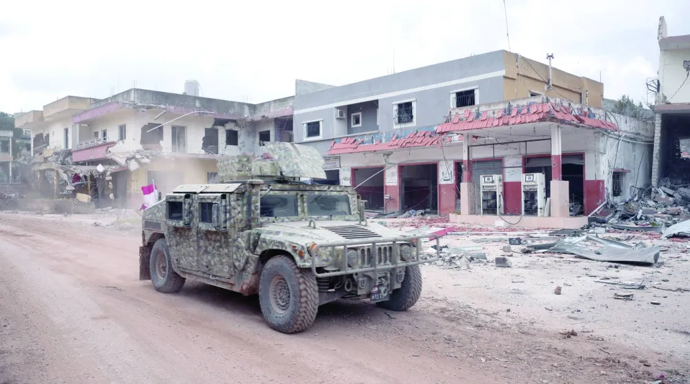 آلية للجيش اللبناني في بلدة ميس الجبل جنوب لبنان تعبر قرب أبنية متضررة جراء الحرب (أرشيفية - رويترز)