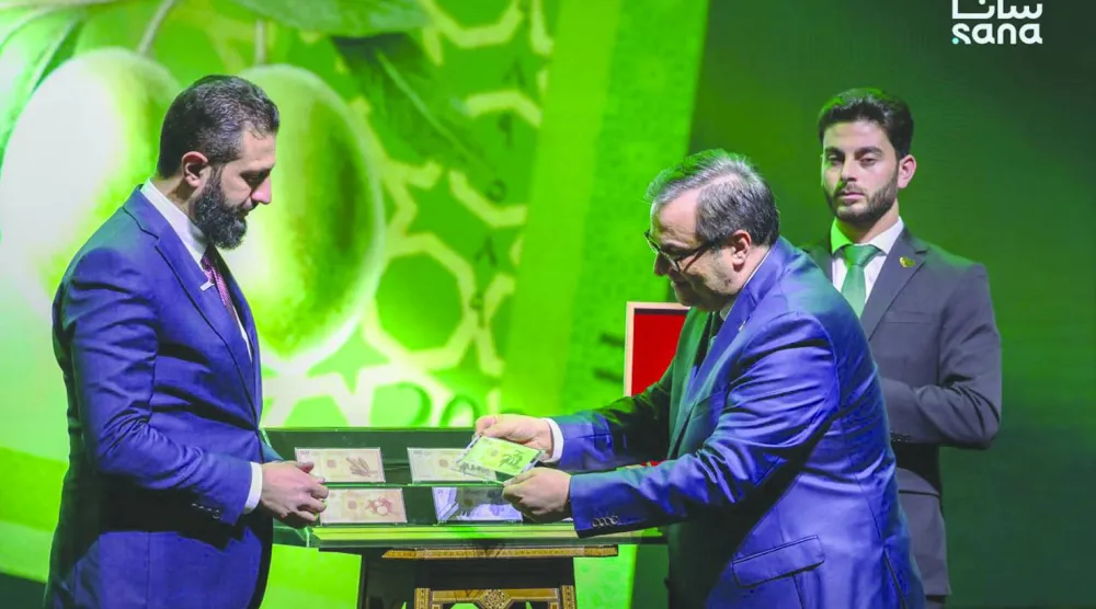 الرئيس السوري أحمد الشرع وحاكم مصرف سوريا المركزي عبد القادر الحصرية خلال إطلاق العملة السورية الجديدة (سانا)