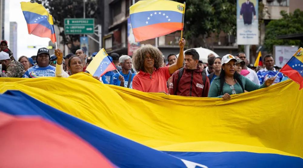 شخص يحمل العلم الفنزويلي خلال مسيرة نظمها أنصار شافيز في كراكاس فنزويلا (إ.ب.أ)