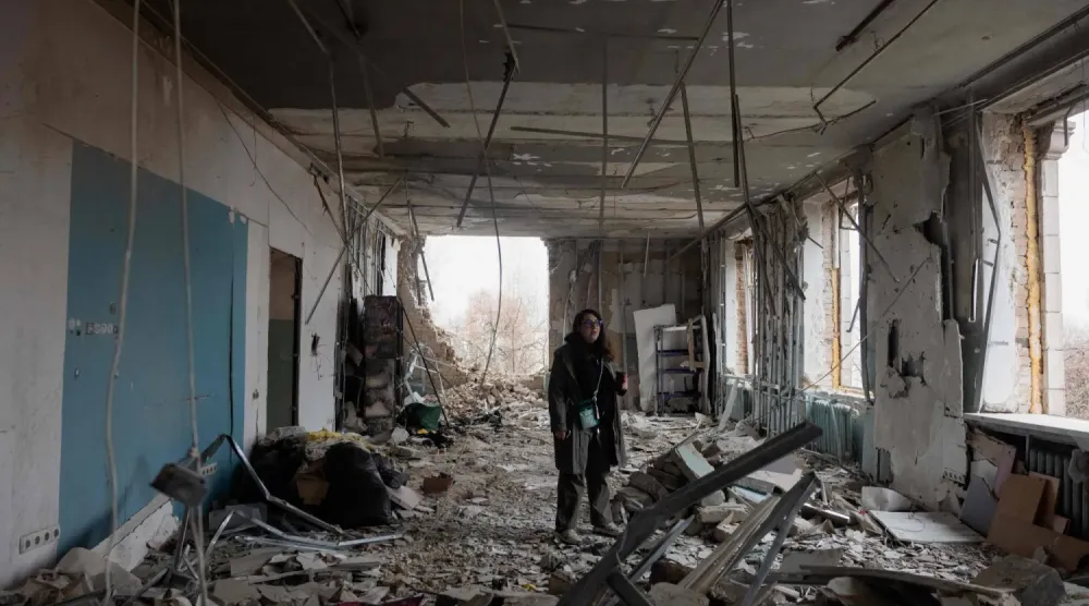 Kiev'de yıkılmış bir evin ortasında duran kadın (AFP)