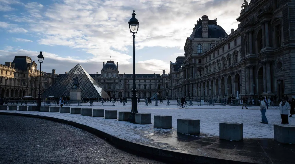 This photograph shows a general view of the Louvre Museum, with the Louvre pyramid (L) designed by Chinese-US architect Ieoh Ming Pei, after the first snowfall of the year in Paris on January 3, 2026. (Photo by Blanca CRUZ / AFP) 