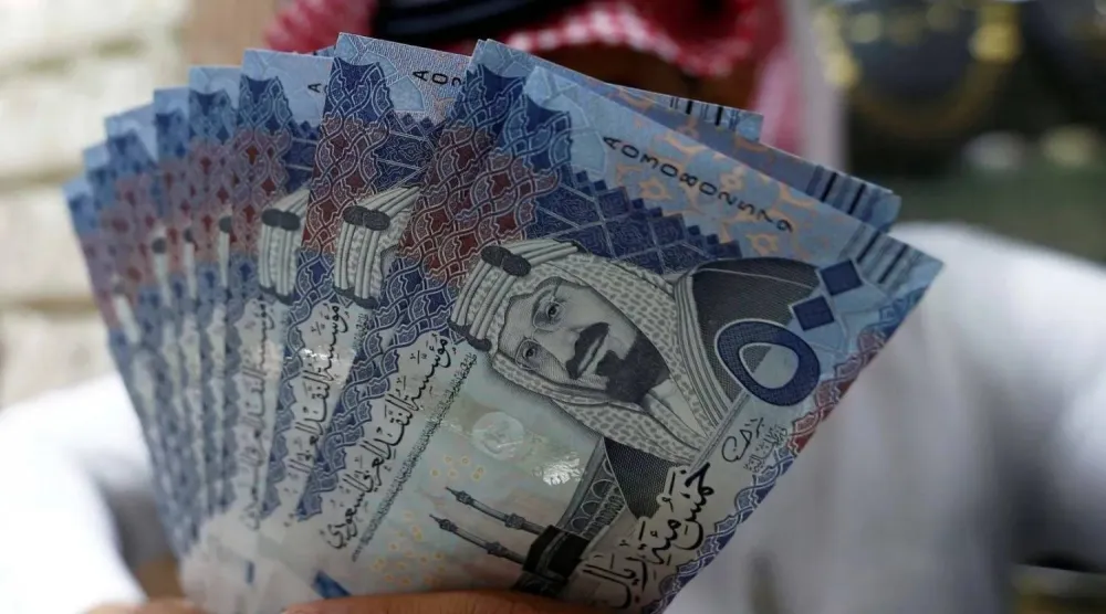 صراف سعودي يعرض أوراقاً نقدية بالريال السعودي في محل صرافة (رويترز)