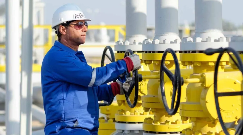 فني يدير صمام الفتح والإغلاق في منشأة للغاز تابعة لشركة «دانة غاز» الإماراتية (دانة غاز)
