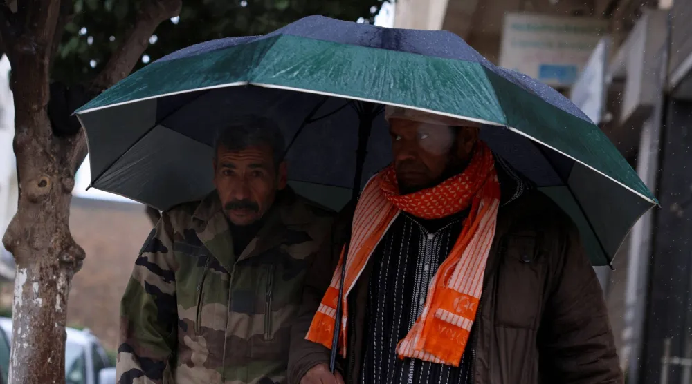 مغربيان يحتميان من الأمطار الغزيرة التي ضربت مدينة فاس المغربية لأيام متواصلة (رويترز)