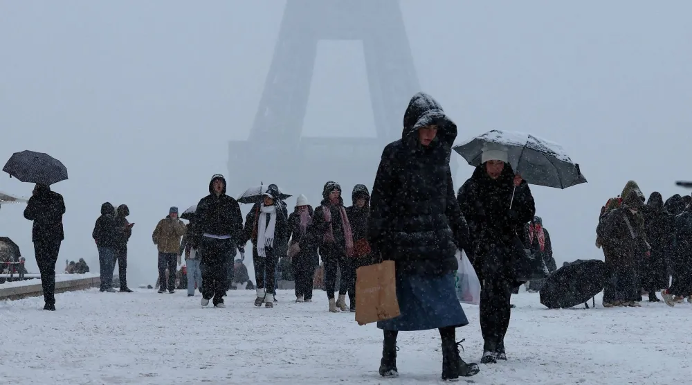 أشخاص يسيرون في ساحة تروكاديرو المغطاة بالثلوج بالقرب من برج إيفل بباريس مع اجتياح موجة برد قارس وتساقط الثلوج 5 يناير 2026 (رويترز)