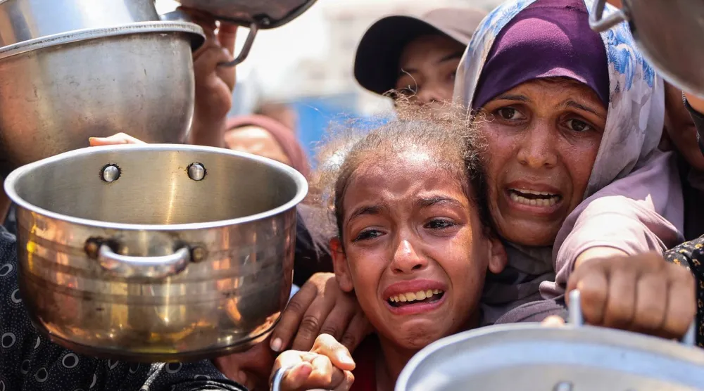 فلسطينيون يتجمعون لتسلُّم وجبات طعام مطبوخة من مركز توزيع أغذية في مدينة غزة (أ.ف.ب)