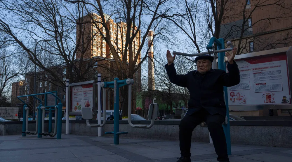 رجل مسن يمارس الرياضة بالقرب من مجمع سكني في منطقة تشانغبينغ على مشارف بكين (أ.ب)