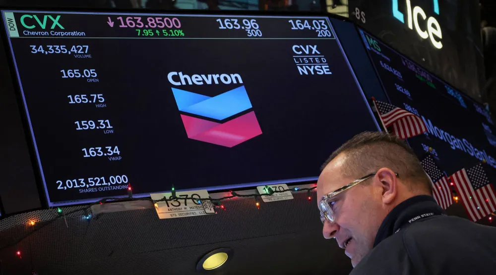 متداول يعمل في قاعة بورصة نيويورك بينما تعرض شاشة معلومات التداول الخاصة بشركة «شيفرون» (رويترز) 