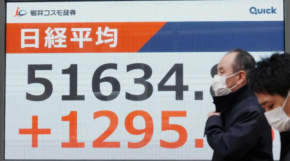 رجل يمر أمام شاشة إلكترونية تعرض حركة الأسهم في وسط العاصمة اليابانية طوكيو (أ.ف.ب)