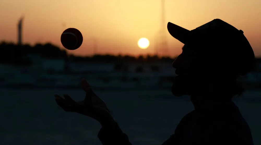 عامل أجنبي يلعب الكريكيت يظهر كظلال أمام غروب الشمس في الدوحة في اليوم الأول من العام الجديد (أ.ف.ب)