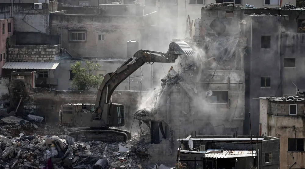 حفَّارة عسكرية إسرائيلية أثناء هدم أحد المباني السكنية في مخيم نور شمس بالضفة الغربية (أ.ف.ب)