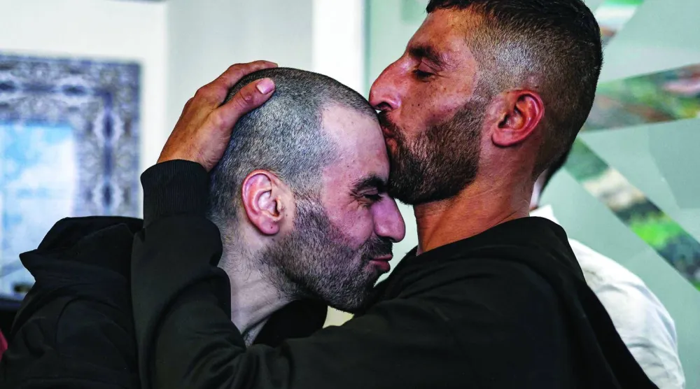 أسير فلسطيني محرَّر (يسار) يُقبِّله شقيقه لدى وصوله إلى رام الله قادماً من سجن عوفر الإسرائيلي (أ.ف.ب)