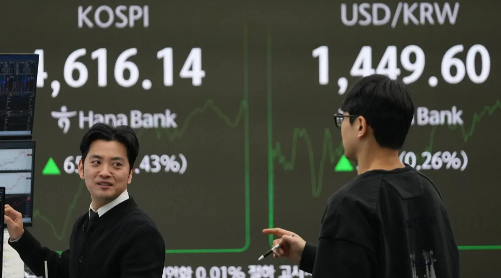 متداولون يتحدثون قرب شاشات تعرض مؤشر «كوسبي» وسعر صرف الدولار الأميركي مقابل الوون في بنك هانا في سيول (أ.ب)