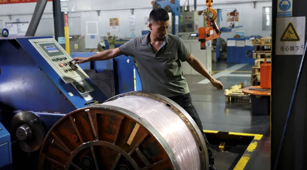 عامل على خط إنتاج أسلاك النحاس في مصنع بمدينة قانتشو الصينية (رويترز)