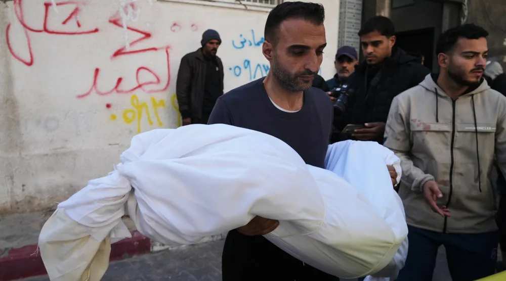 فلسطيني يحمل جثمان طفلة عمرها 11 سنة قُتلت بنيران إسرائيلية في جباليا أثناء تشييعها من مستشفى الشفاء بمدينة غزة يوم الخميس (أ.ب)