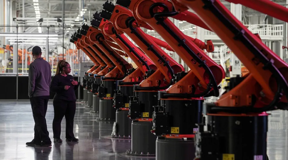 أشخاص بجانب أذرع روبوتية في مصنع بطاريات «مرسيدس - بنز» الكهربائية بوودستوك بألاباما (رويترز)