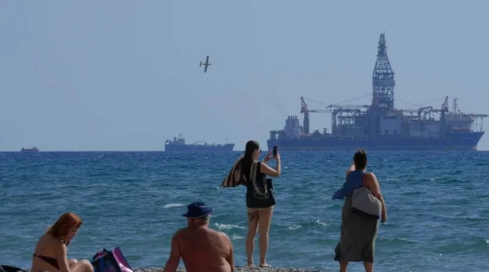 أشخاص على الشاطئ يلتقطون صوراً لسفينة الحفر «تنغستن إكسبلورر» في مدينة لارنكا الساحلية (أ.ب)