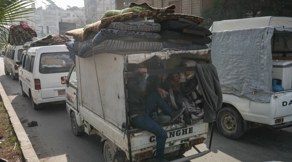 سوريون يستقلون شاحنة صغيرة في حلب أمس فيما يواصل آلاف المدنيين النزوح جراء الاشتباكات بين الجيش و"قسد" (إ.ب.أ)