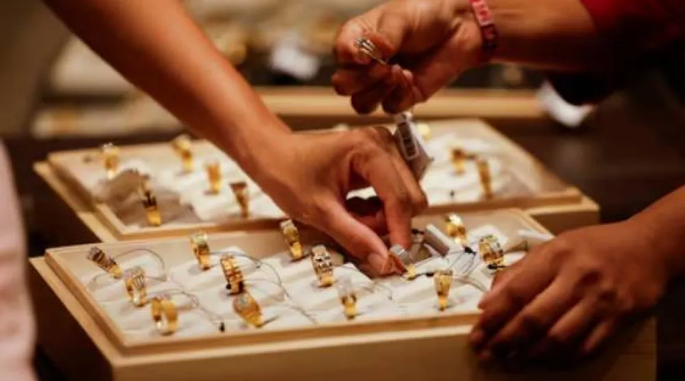 يعرض بائع خاتماً ذهبياً على زبائن داخل صالة عرض للمجوهرات في أحمد آباد بالهند (رويترز)