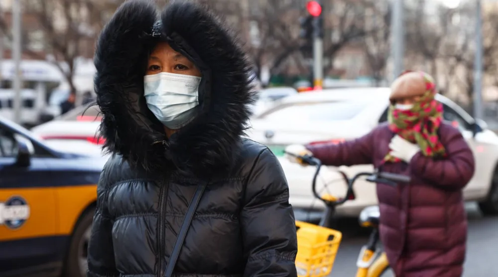 امرأة مسنة ترتدي كمامة تسير في أحد شوارع بكين (إ.ب.أ)