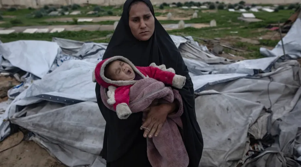 Güçlü rüzgar ve yağmur nedeniyle Gazze Şeridi'nin güneyindeki Han Yunus'ta çadırı yıkılan Filistinli bir kadın bebeğiyle (EPA)