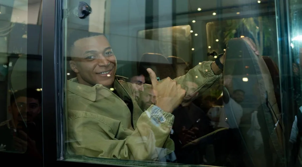 مبابي يشير للكاميرا من على متن السيارة التي أقلته إلى فندق البعثة (وزارة الرياضة)