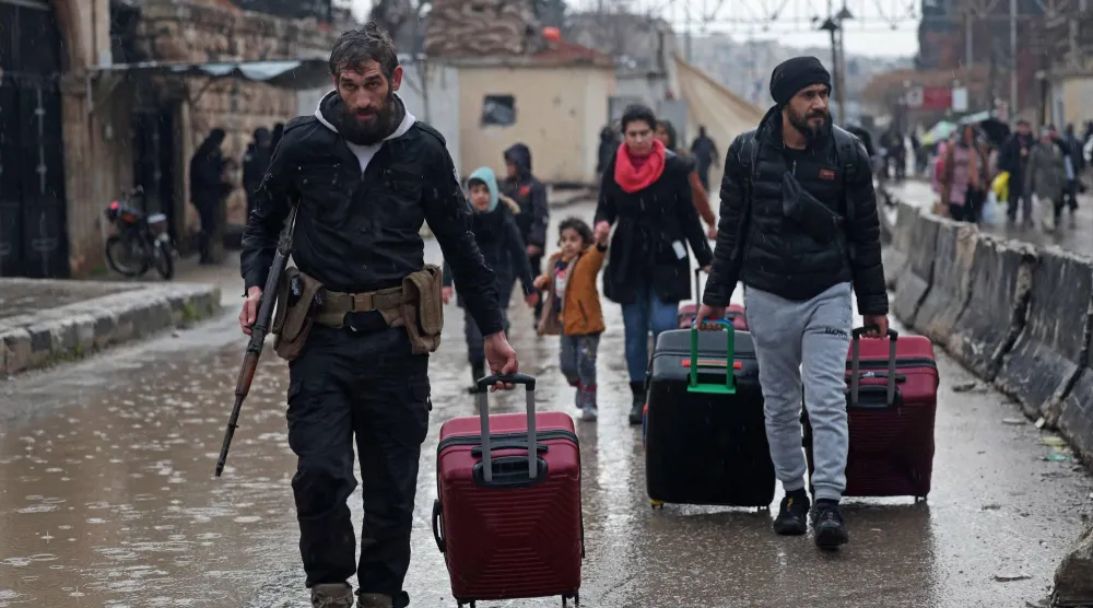 TOPSHOT - Residents of Aleppo's Sheikh Maqsud area evacuate their neighborhood after warnings from the Syrian army that called on civilians to get out of harms way, following the refusal of Kurdish fighter forces to leave Aleppo, on January 9, 2026. (Photo by OMAR HAJ KADOUR / AFP)