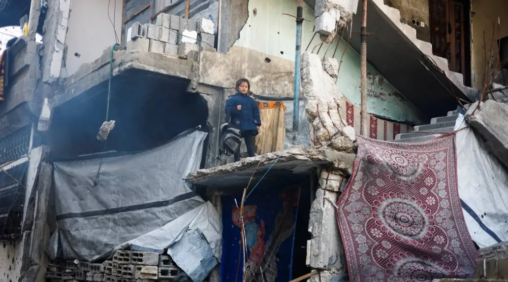 Filistinli kız çocuğu, Gazze Şeridi'nin kuzeyindeki Cibaliye'de yıkılmış bir binadan dışarı bakıyor (Reuters)