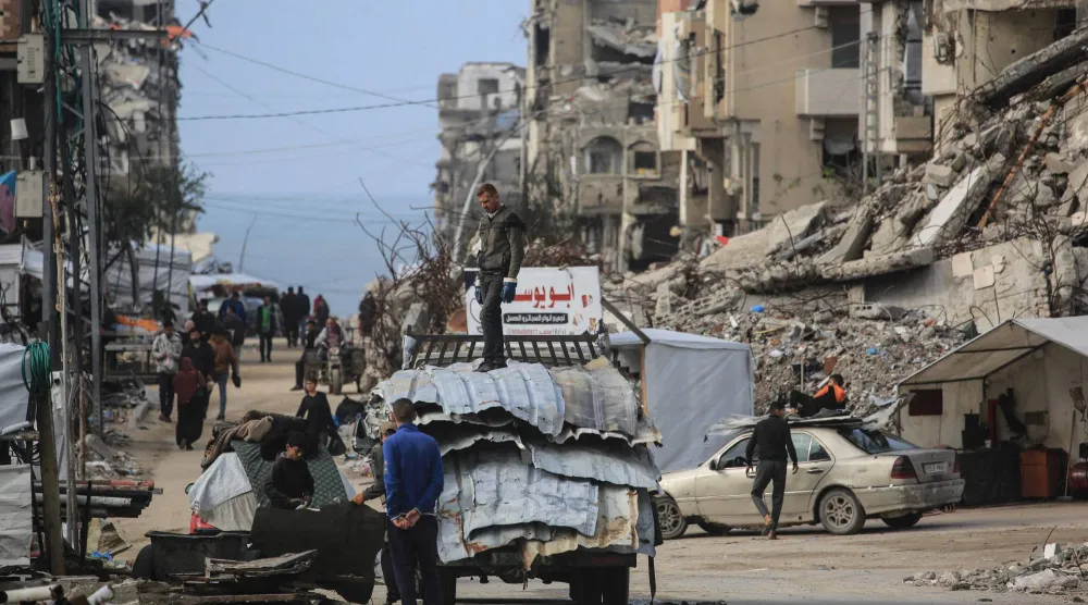 فلسطينيون يشقون طريقهم وسط المباني المتضررة جراء الحرب في جباليا بشمال قطاع غزة (أ.ف.ب)