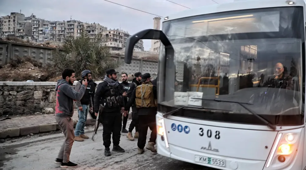 SDG üyelerini taşıyan bir otobüs, Halep'in Şeyh Maksud mahallesinden ayrılırken (EPA)