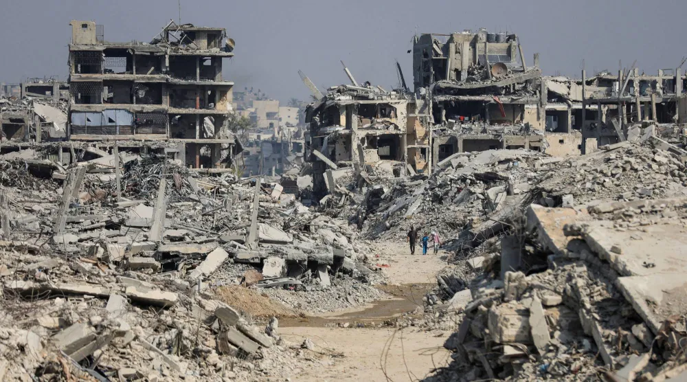 فلسطينيون يمشون بين المباني المدمرة بفعل الغارات الإسرائيلية في مدينة غزة نوفمبر الماضي (رويترز)