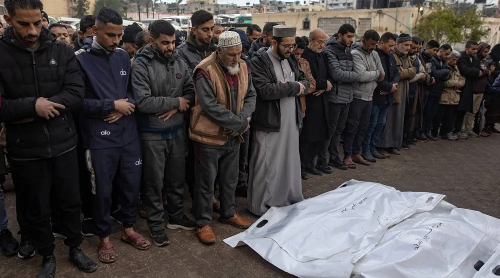 فلسطينيون يُصلُّون على جثامين ذويهم ضحايا الغارات الإسرائيلية على خان يونس بجنوب قطاع غزة (إ.ب.أ)