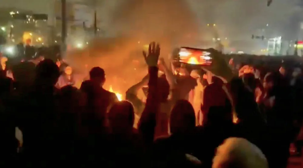 متظاهرون يرقصون حول نار مشتعلة في شارع وسط طهران (أ.ب)