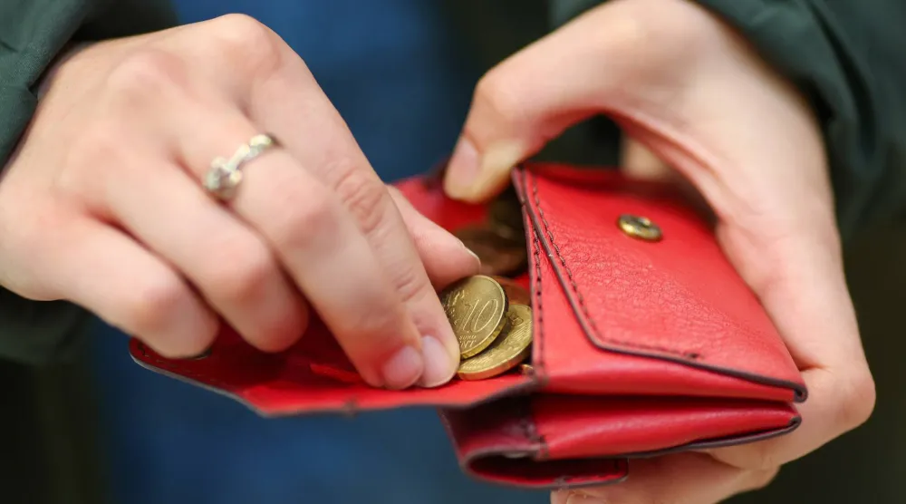 امرأة تعدّ النقود المعدنية داخل محفظة حمراء في ألمانيا (د.ب.إ)