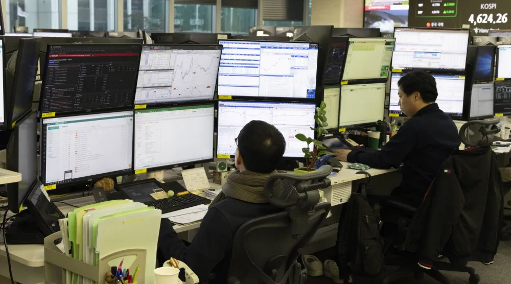 متداولون كوريون يتابعون أعمالهم أمام شاشات التداول ببنك «هانا» في سيول (إ.ب.أ)