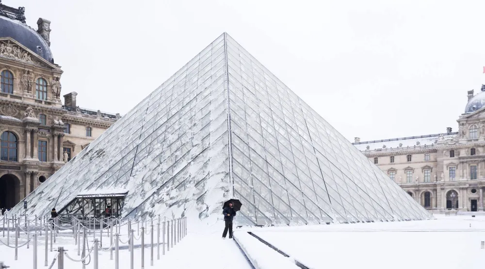 People walk next to the Louvre Museum covered in snow in Paris, France, 07 January 2026. (EPA)