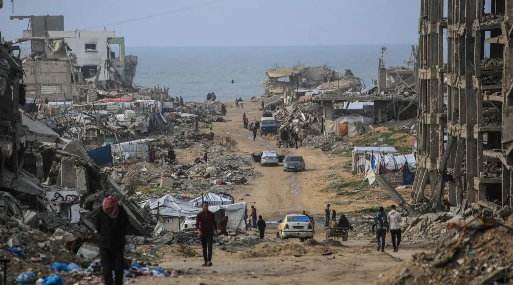 Palestinians walk along a road amid destroyed buildings in Jabalia, in the northern Gaza Strip, on January 10, 2026. (AFP)