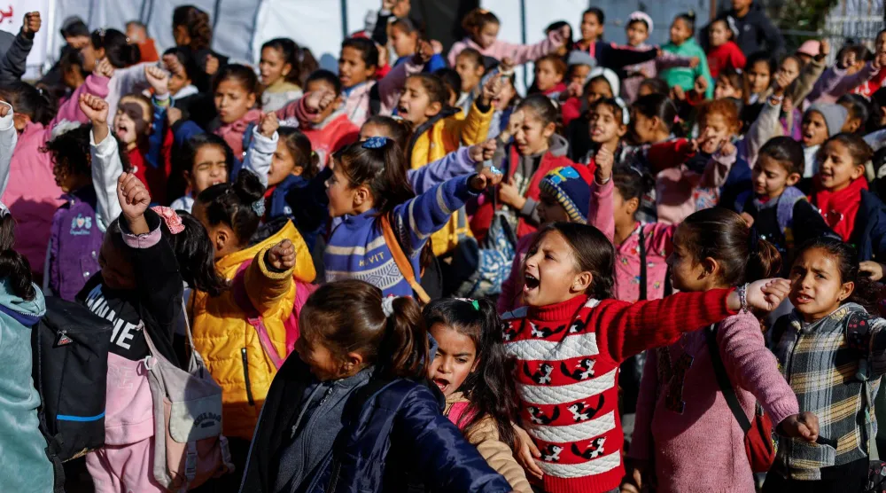 طلاب فلسطينيون نازحون يتجمعون خارج خيمة قرب «الخط الأصفر» الذي حددته إسرائيل في بيت لاهيا شمال قطاع غزة يوم 6 يناير الحالي (رويترز)