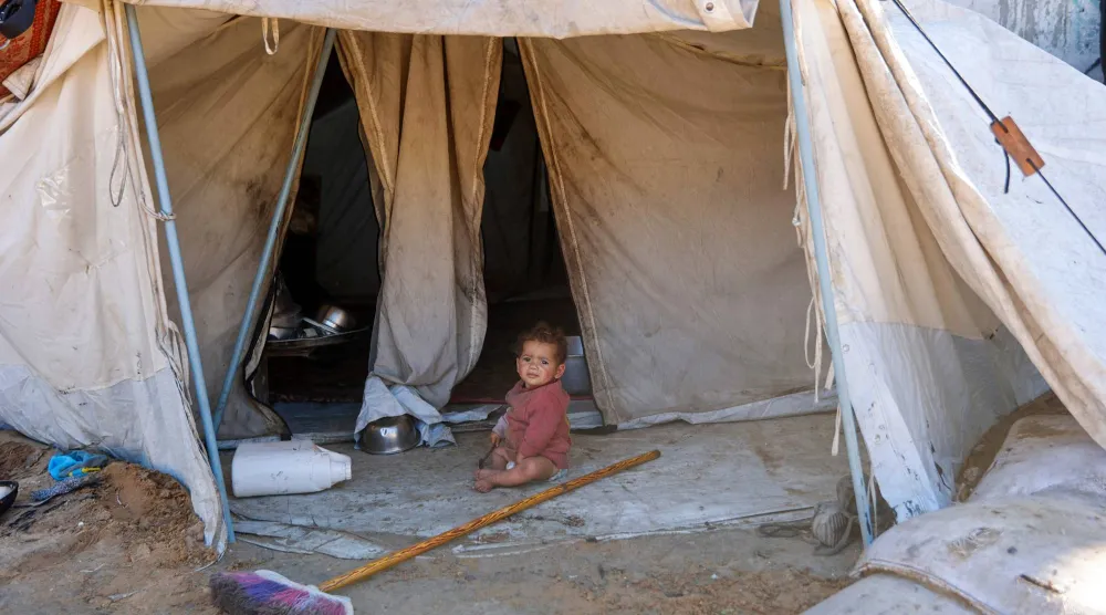 طفل فلسطيني يجلس أمام خيمة في مدينة غزة (أ.ف.ب) 