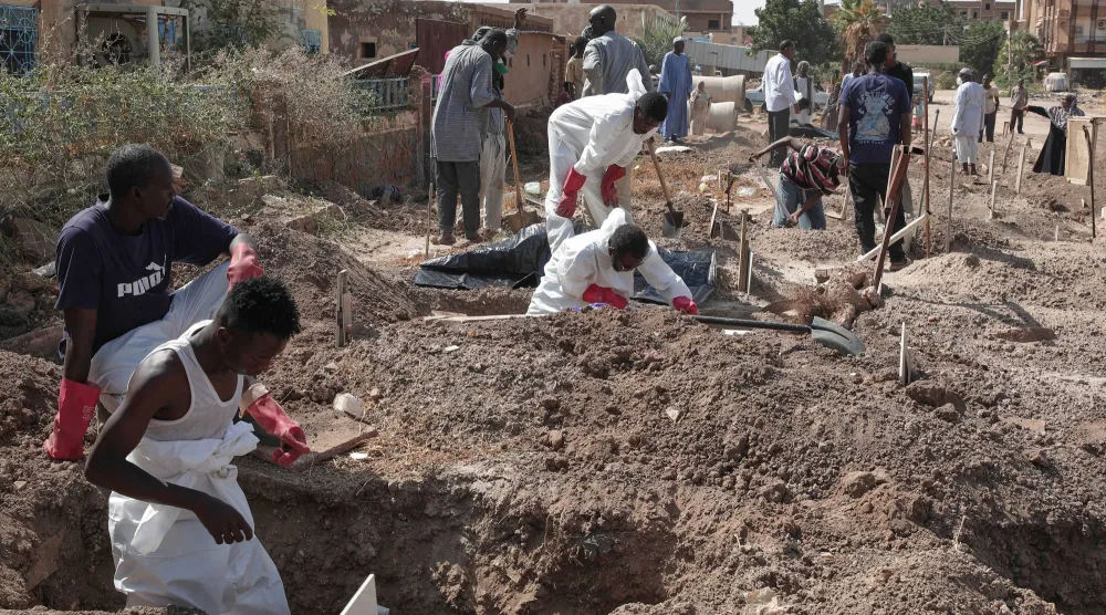 أفراد من الصليب الأحمر السوداني يعيدون دفن ضحايا الحرب في مقبرة محلية بالخرطوم يوم الأحد (أ.ب)